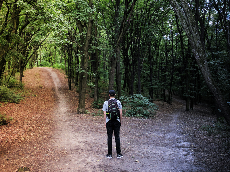 A man in a forest makes a decision of what path to follow.