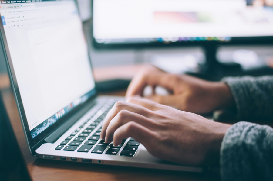 Photo of a man typing on a laptop.